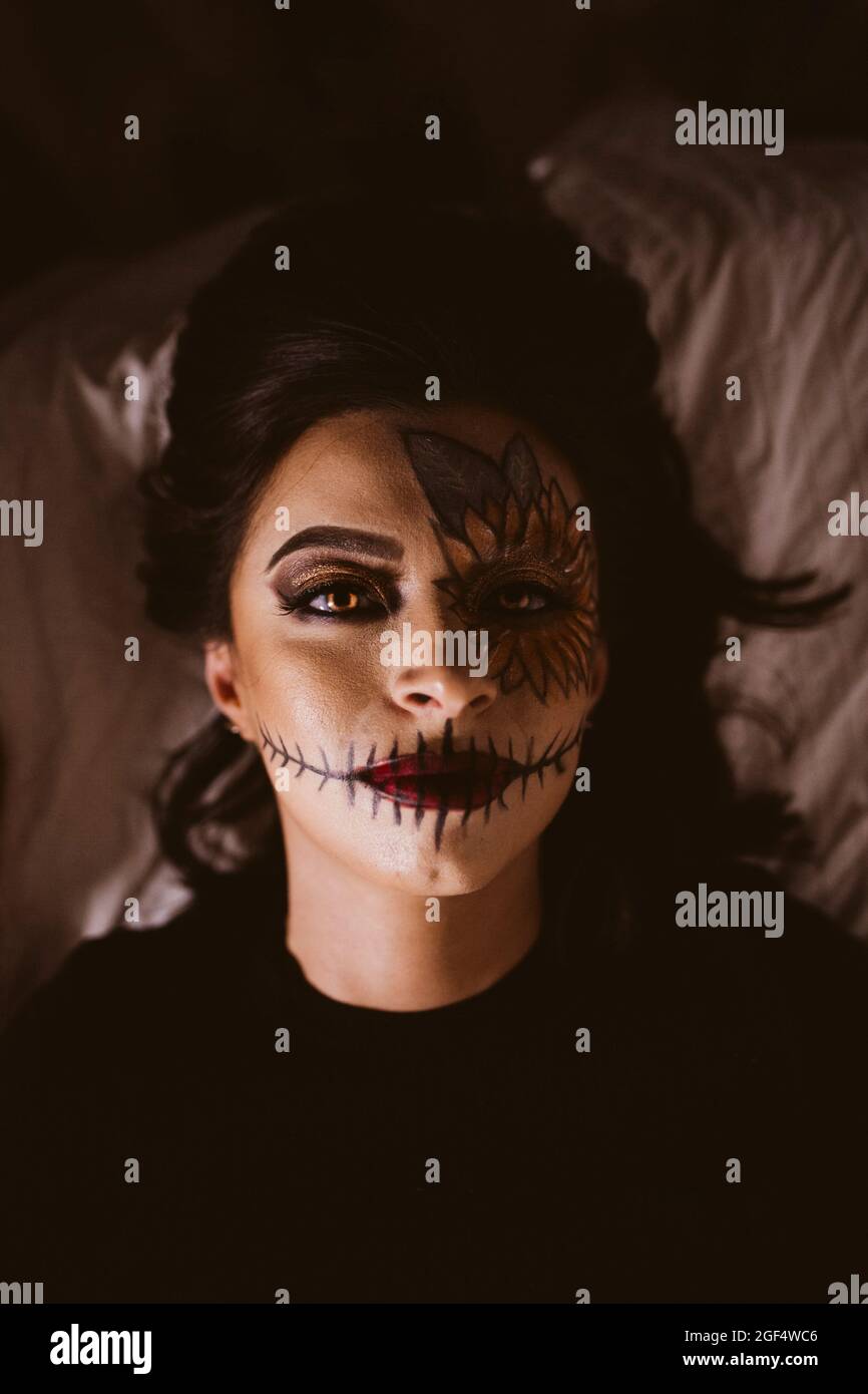 Frau mit zeremoniellem Make-up liegt an Halloween auf dem Bett Stockfoto