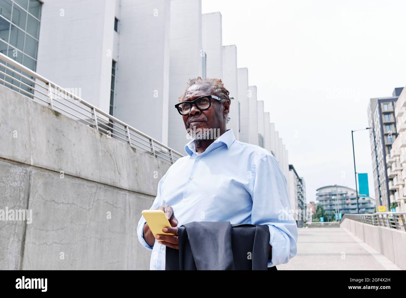 Leitender männlicher Profi mit Mobiltelefon und Blazer Stockfoto
