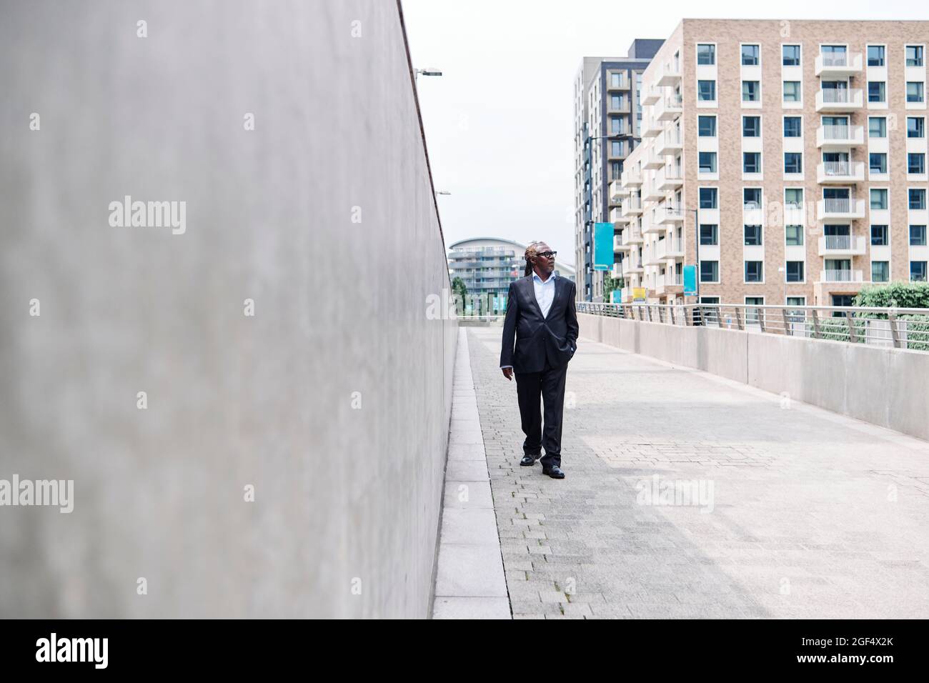 Älterer männlicher Profi mit der Hand in der Tasche, der auf dem Fußweg läuft Stockfoto