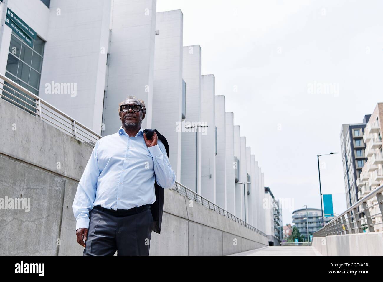 Älterer Profi, der Blazer hält, während er vor dem Gebäude läuft Stockfoto