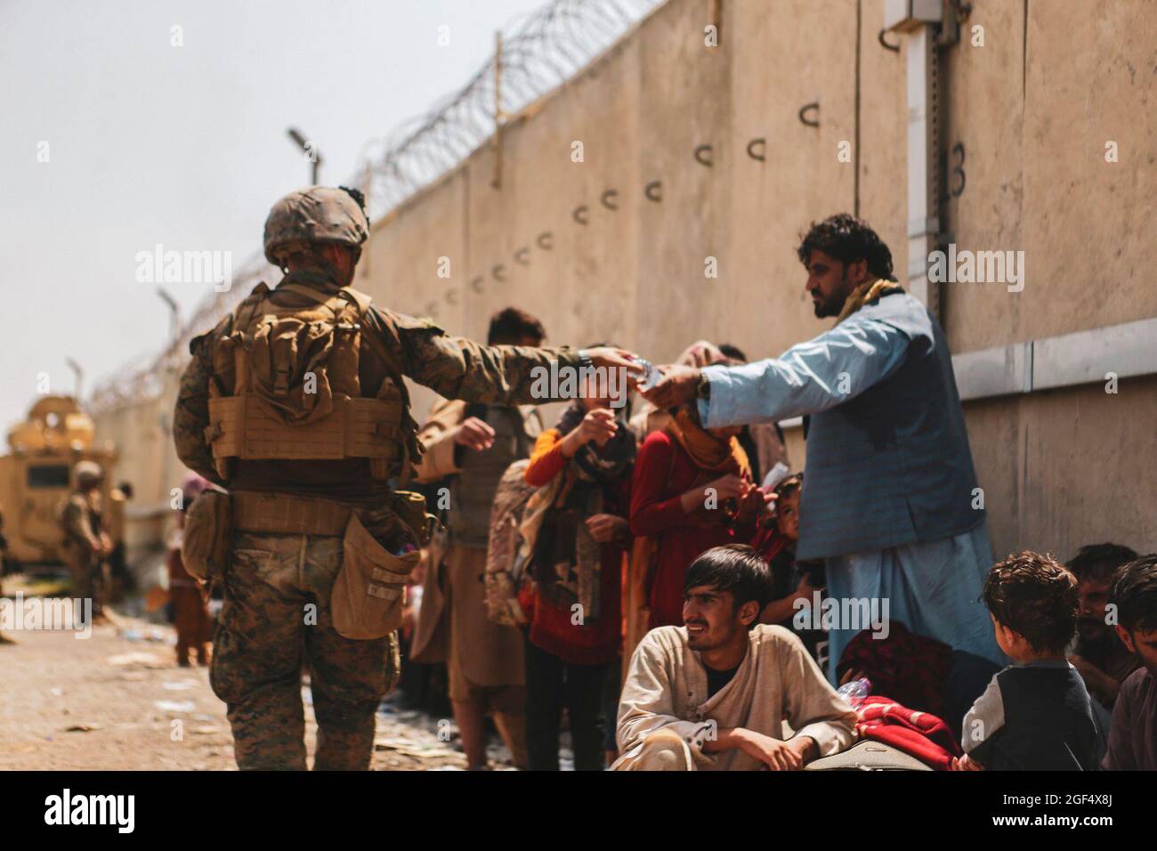 Eine Marine mit der 24. Marine Expeditionary Unit (MEU) leitet während einer Evakuierung am Hamid Karzai International Airport, Kabul, Afghanistan, Wasser an Evakuierte weiter, 22. August 2021. US-Dienstmitglieder unterstützen das Außenministerium bei einer nicht-kämpferischen Evakuierungsoperation (NEO) in Afghanistan. Kreditpflicht: Isaiah Campbell/US Marine Corps über CNP Stockfoto