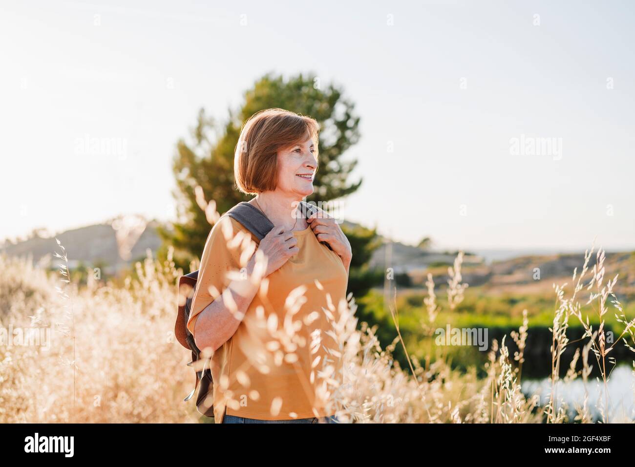 Ältere Frau mit kurzen Haaren, die an sonnigen Tagen wandern Stockfoto