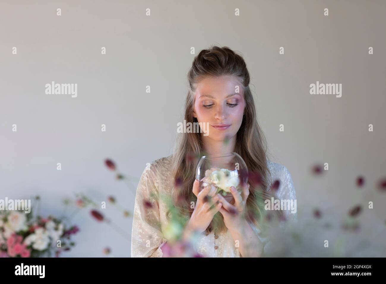 Junge Frau mit Terrarienschale und duftenden Rosen Stockfoto