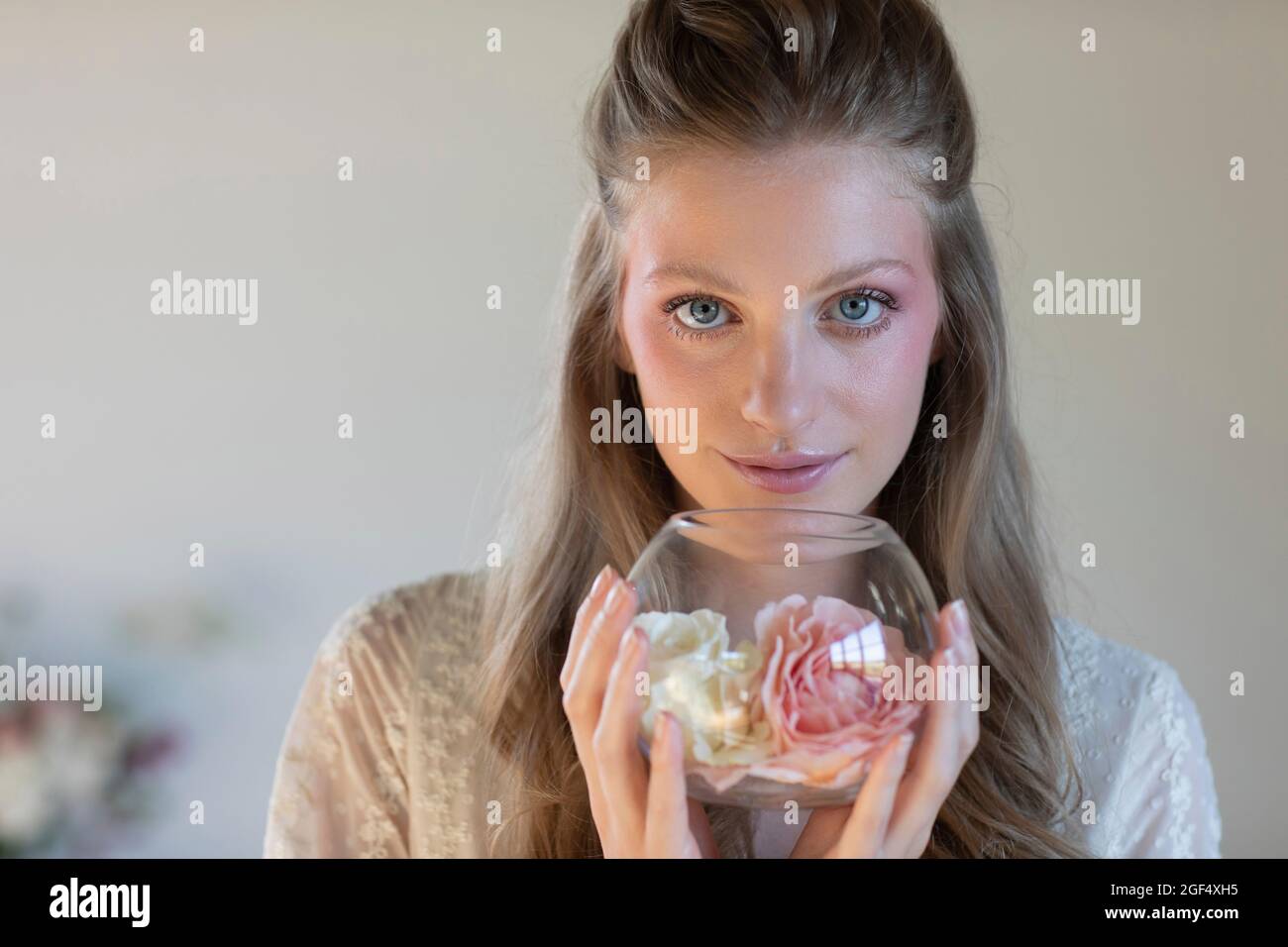Schöne blonde Frau mit duftenden Rosen in einer Glasschale Stockfoto