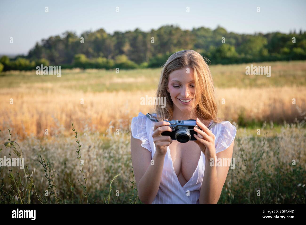 Lächelnde junge Frau, die auf die Kamera schaut, während sie im Feld steht Stockfoto