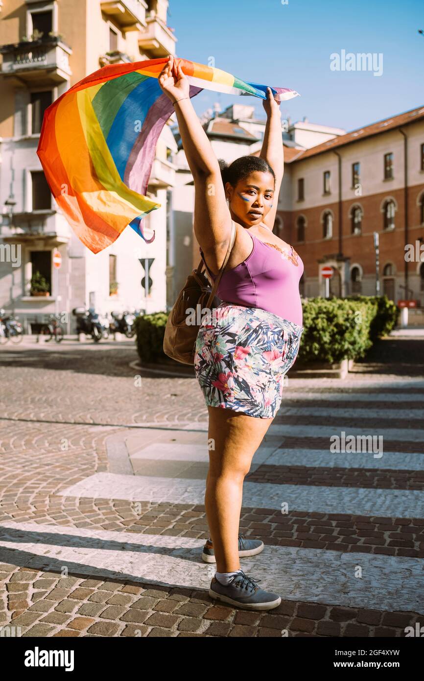 Aktivistin protestiert mit Regenbogenfahne auf der Straße Stockfoto