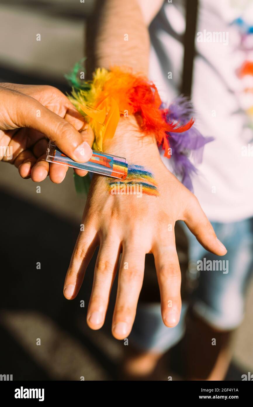 Die Hand des Mannes zeichnet eine Regenbogenfahne auf die Hand eines männlichen Freundes Stockfoto