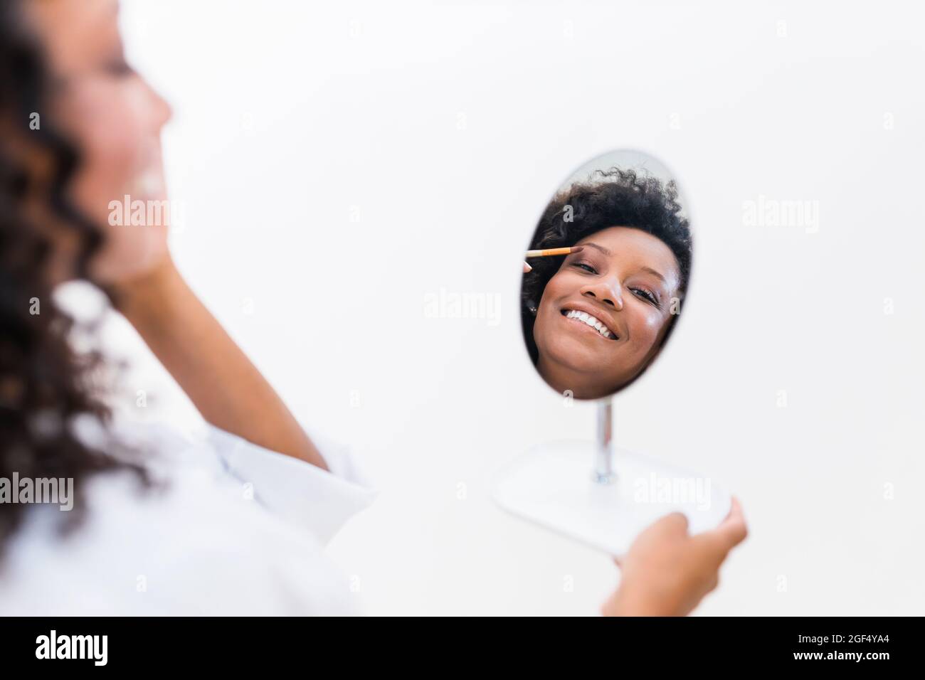 Frau, die Lidschatten anwendet, während sie Spiegelreflexion betrachtet Stockfoto
