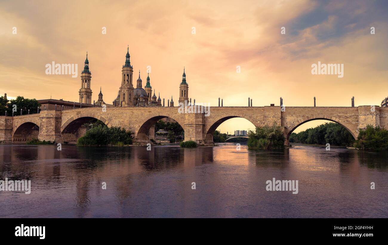 Kathedrale Basilika unserer Lieben Frau von Säule mit Brücke und Ebro Fluss bei Sonnenuntergang. Eine römisch-katholische Kirche im alten Stadtzentrum von Zaragoza. Landmar Stockfoto