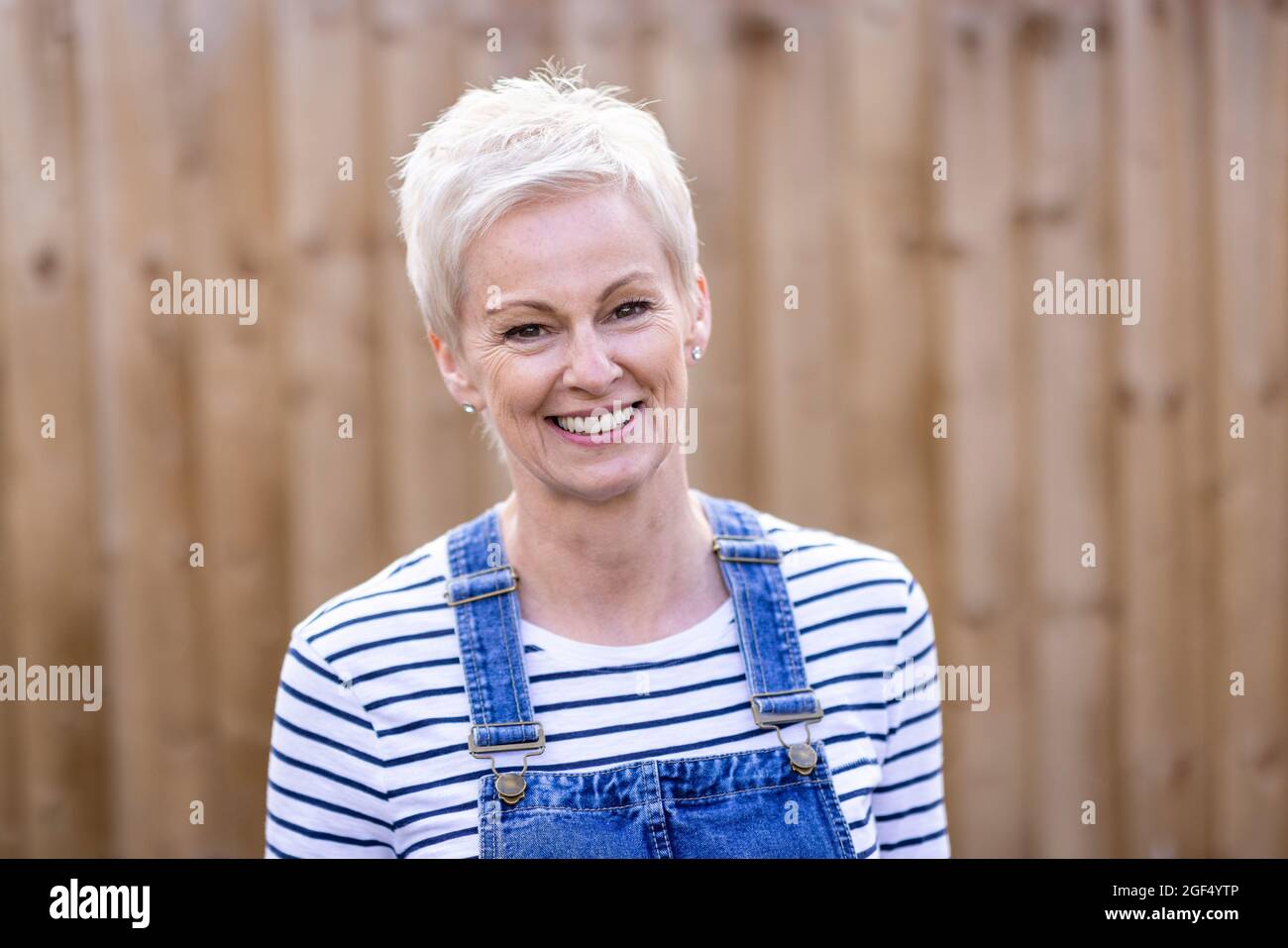 Reife Frau mit kurzen Haaren lächelt im Hinterhof Stockfoto