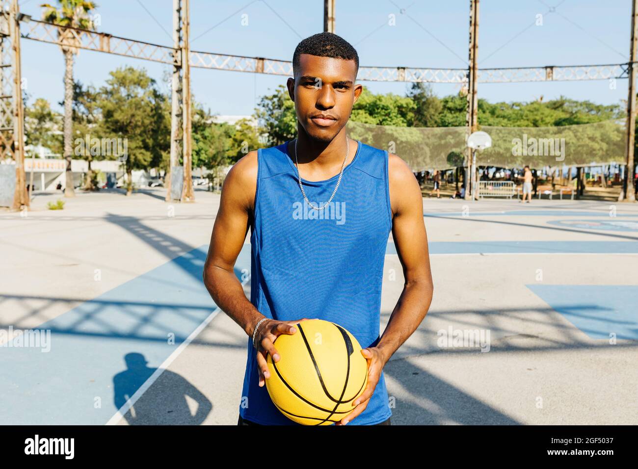 Männlicher Basketballspieler, der Basketball auf dem Sportplatz hält Stockfoto