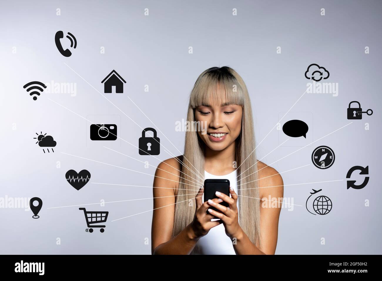 Lächelnde junge Frau mit Mobiltelefon mit Symbolen auf weißem Hintergrund Stockfoto