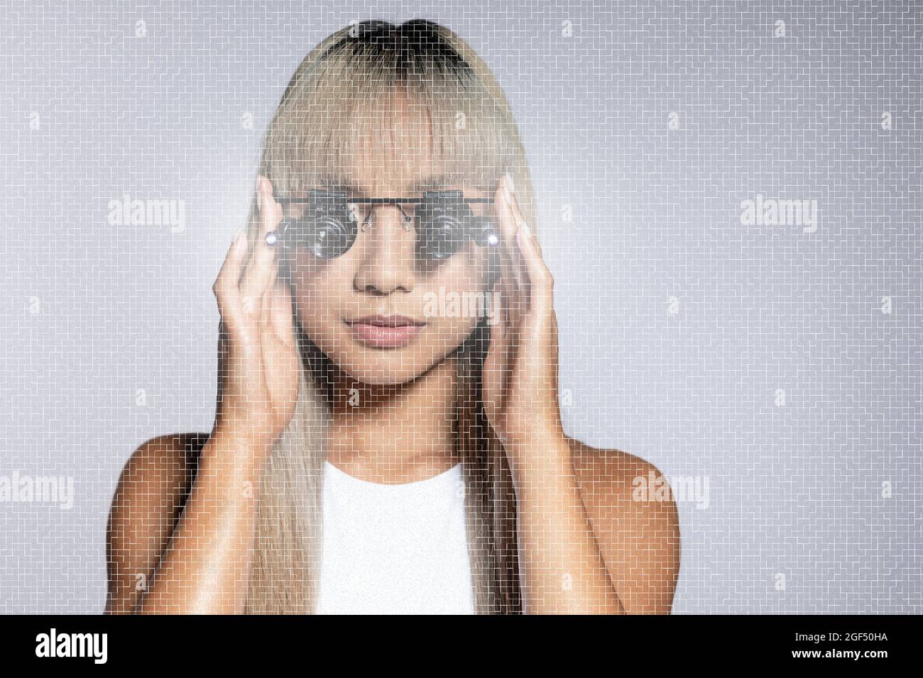 Blonde junge Frau, die Vergrößerungsbrillen auf weißem Hintergrund justiert Stockfoto