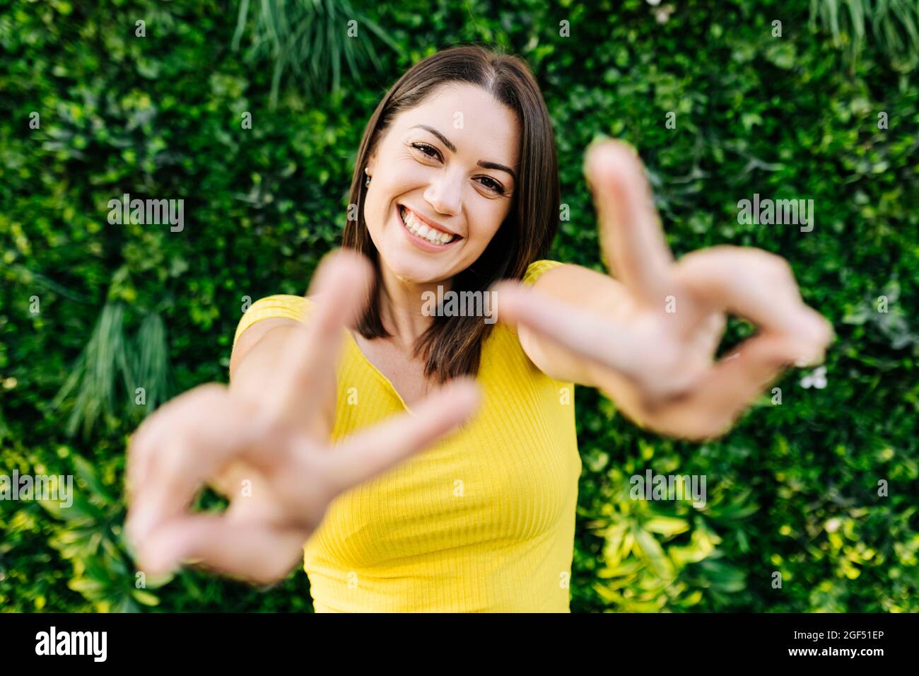 Glückliche junge Frau gestikuliert Friedenszeichen Stockfoto