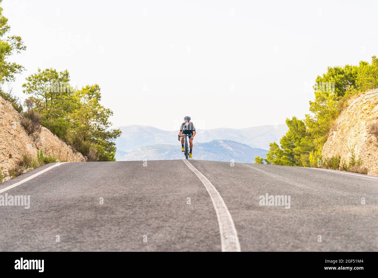 Reifer männlicher Athlet, der auf der Straße Fahrrad fährt Stockfoto