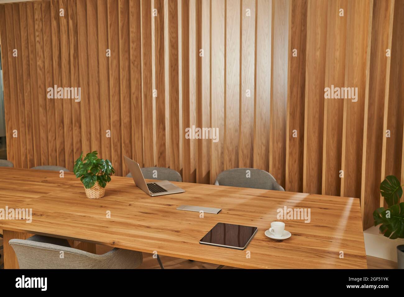 Drahtlose Technologien mit Kaffeetasse und Pflanzen auf einem hölzernen Konferenztisch im Konferenzraum Stockfoto
