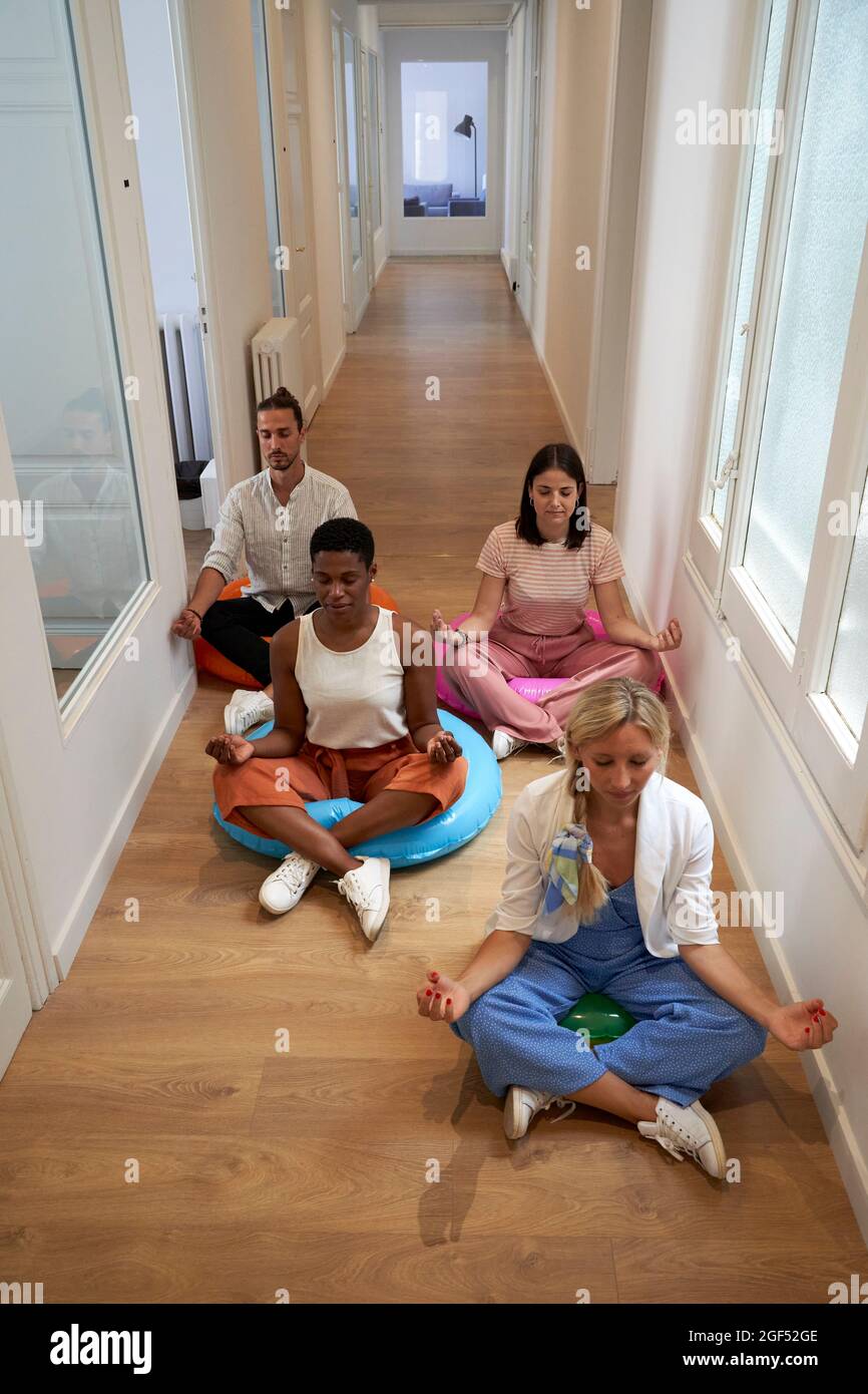 Das Business-Team praktiziert Yoga, während es auf dem Boden sitzt Stockfoto