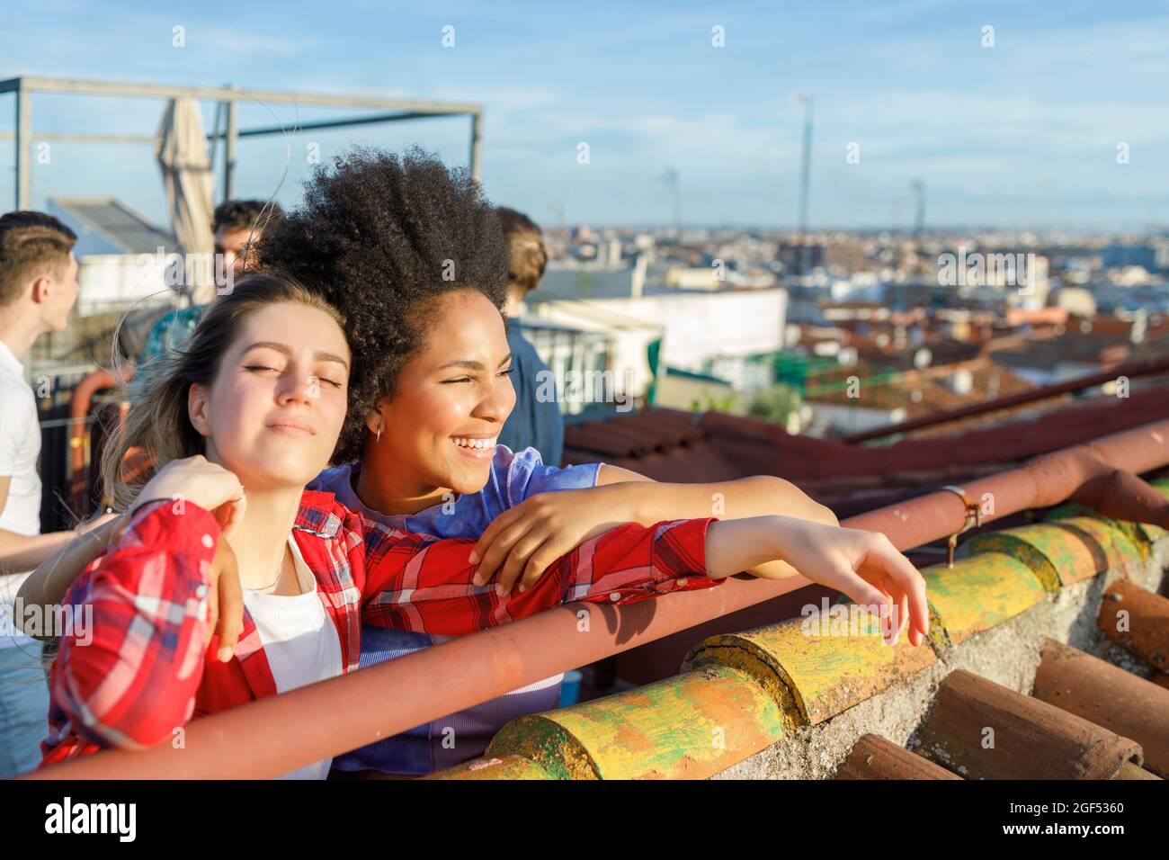 Glückliche junge mutiethnische Freundinnen auf dem Dach Stockfoto