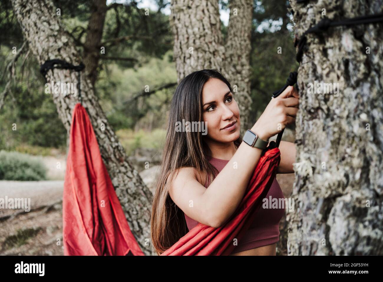 Frau bindet Seil der Hängematte an Baum im Wald Stockfoto