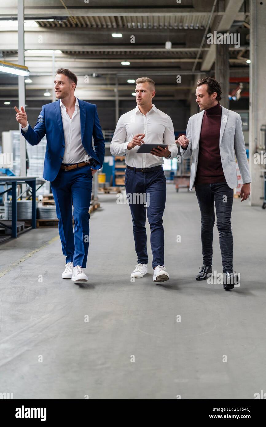 Männliche Fachleute diskutieren beim Gehen in der Industrie Stockfoto