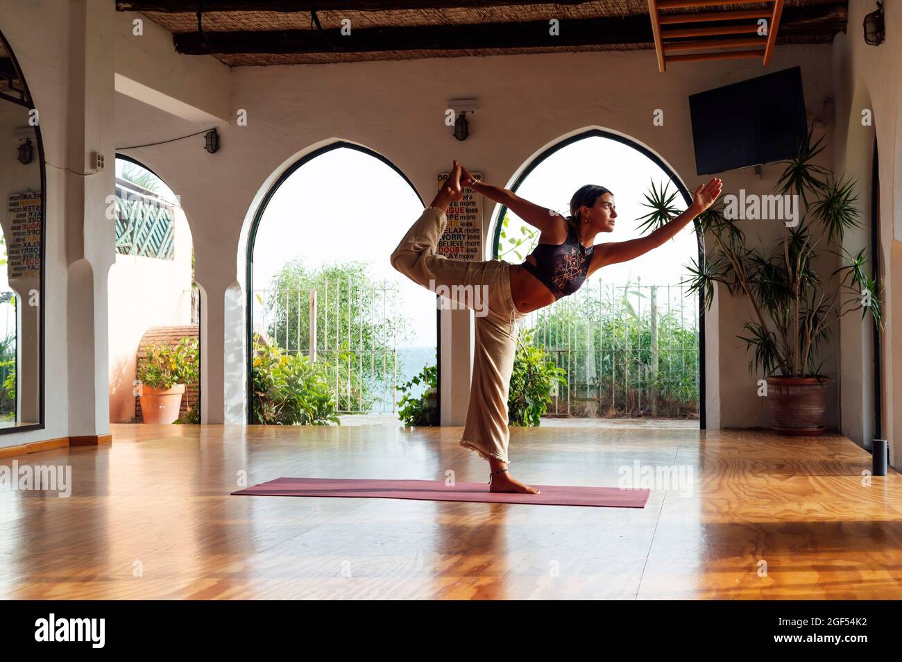 Frau, die Natarajasana praktiziert, während sie Yoga im Fitnessstudio macht Stockfoto