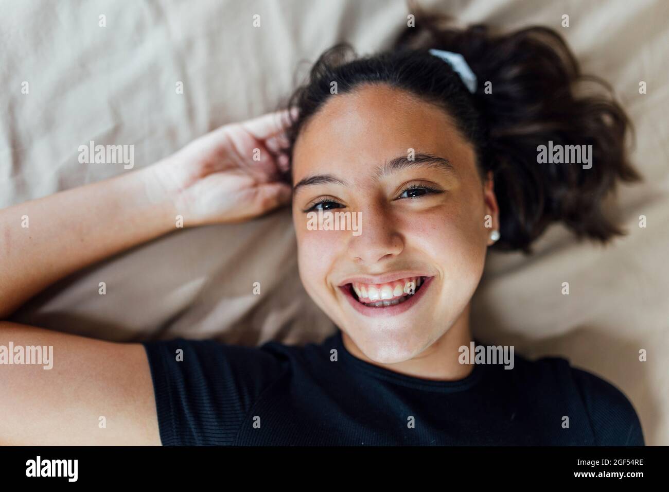 Glückliches Mädchen mit der Hand im Haar auf dem Bett Stockfoto