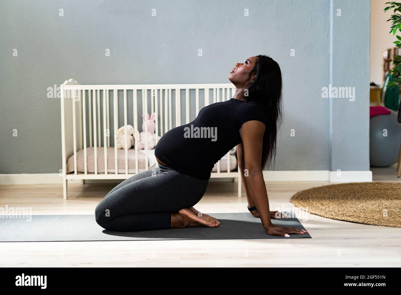 Schwanger junge Frau lehnte sich zurück, während Yoga zu Hause praktiziert Stockfoto