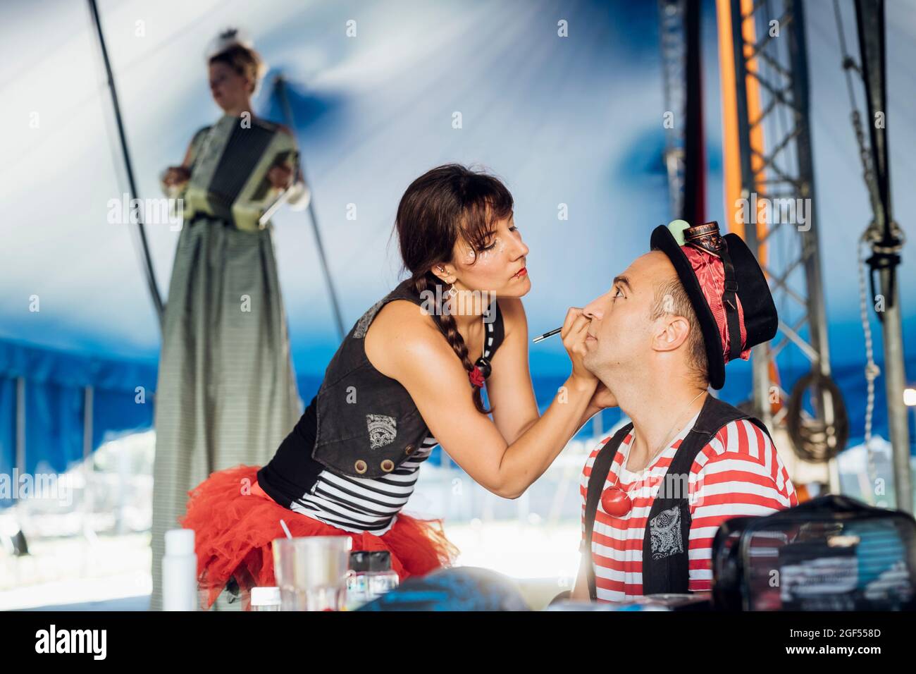 Weibliche Künstlerin, die hinter der Bühne Make-up für männliche Performer macht Stockfoto