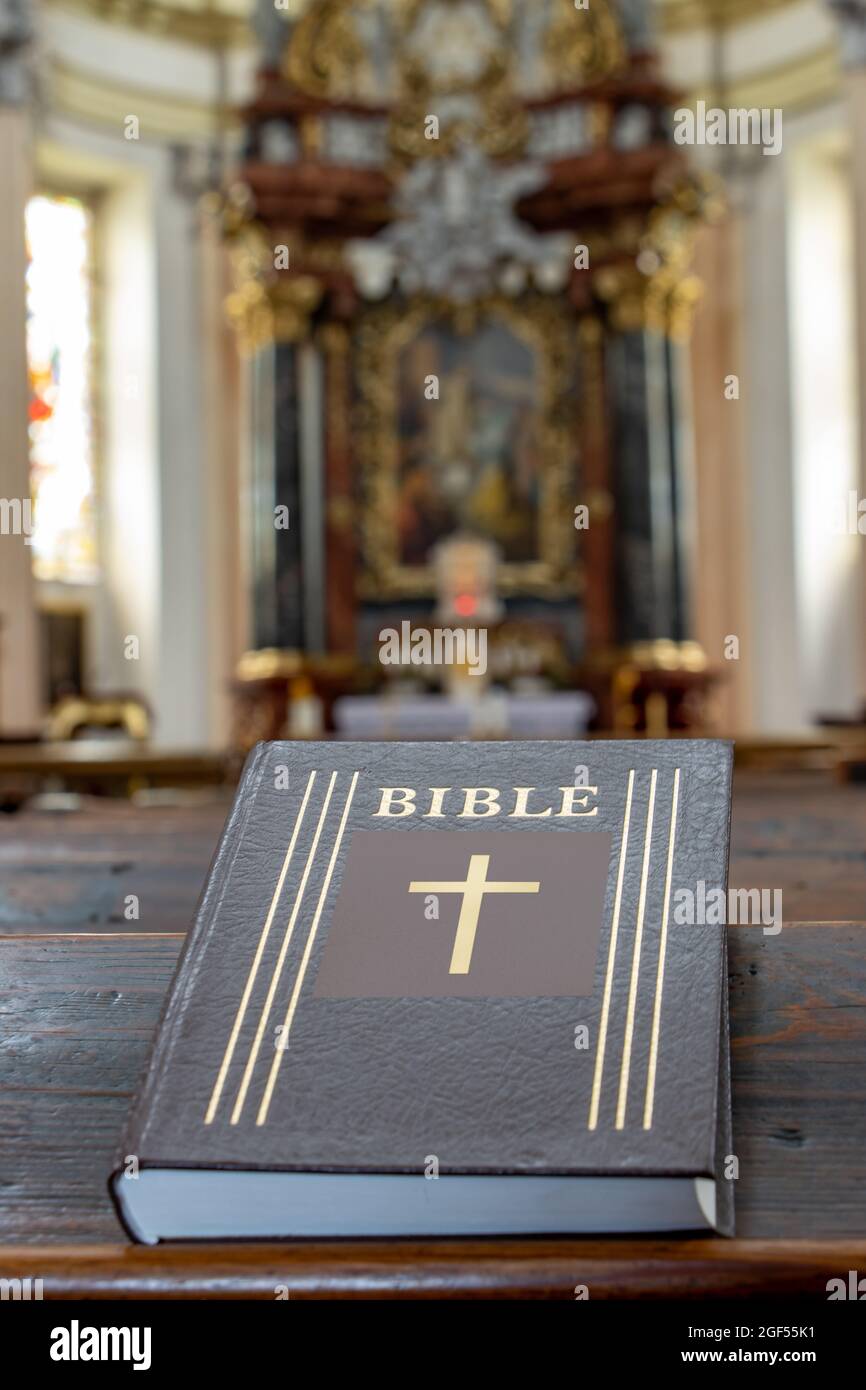 Die Bibel auf dem Tisch einer Gebetsbank in der Kirche mit einem Altar. Stockfoto