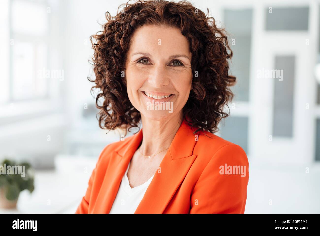 Reife Geschäftsfrau mit lockigen braunen Haaren im Büro Stockfoto