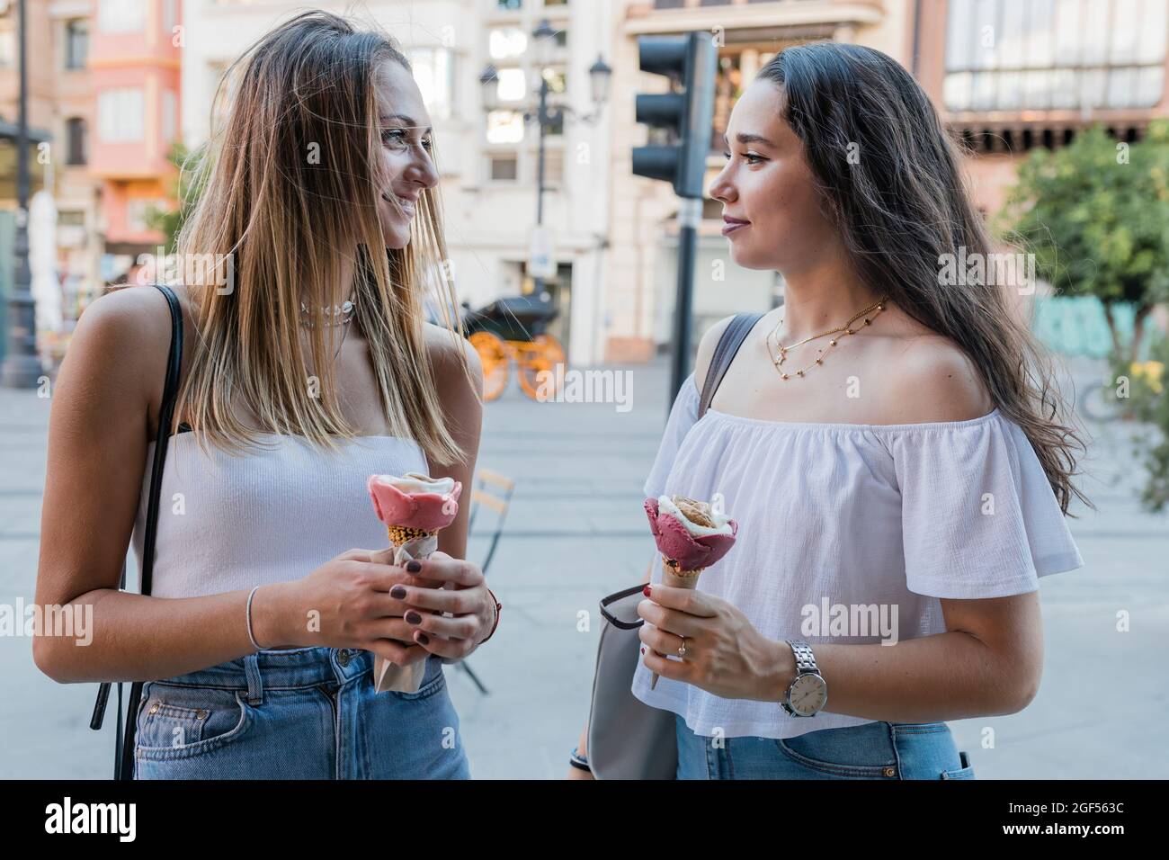 Junge Frauen halten Eiszapfen, während sie sich in der Stadt angucken Stockfoto
