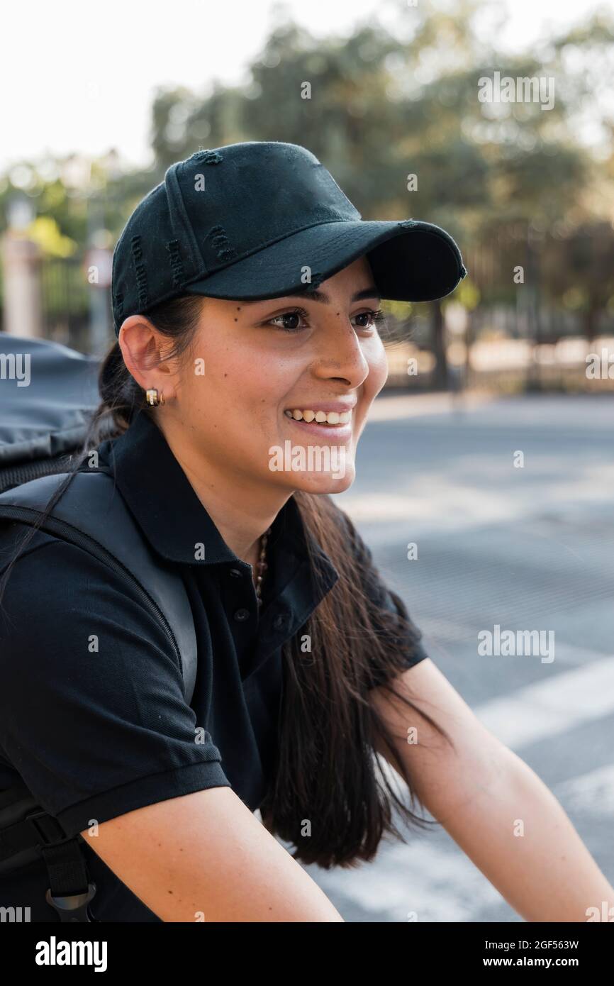 Lächelnder junger, unverzichtbarer Servicemitarbeiter mit schwarzer Mütze Stockfoto
