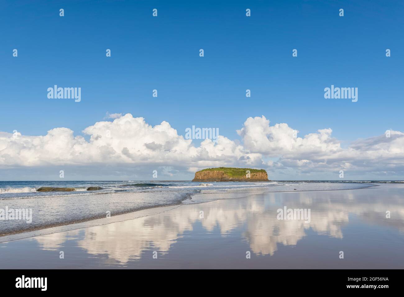 Wolken spiegeln sich im Küstenwasser am Strand von Minnamurra mit Stack Island im Hintergrund Stockfoto