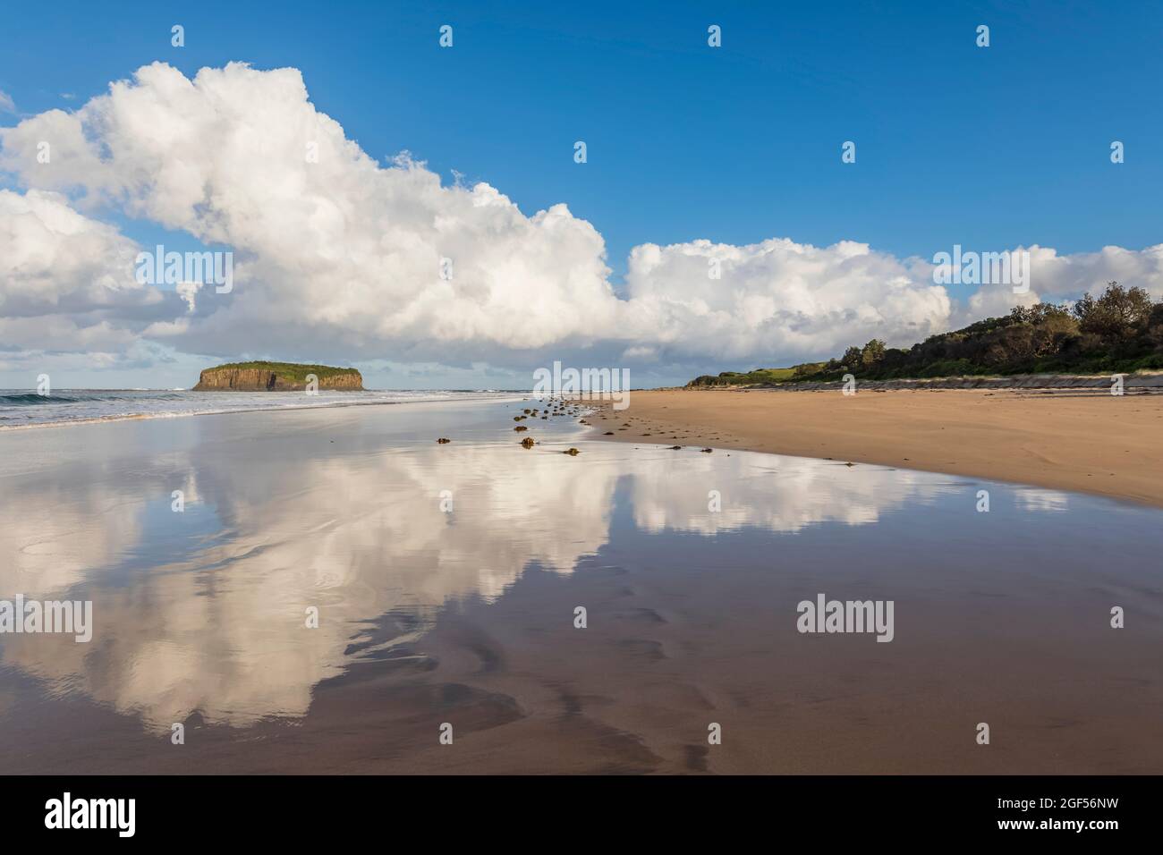 Wolken spiegeln sich im Küstenwasser am Strand von Minnamurra mit Stack Island im Hintergrund Stockfoto