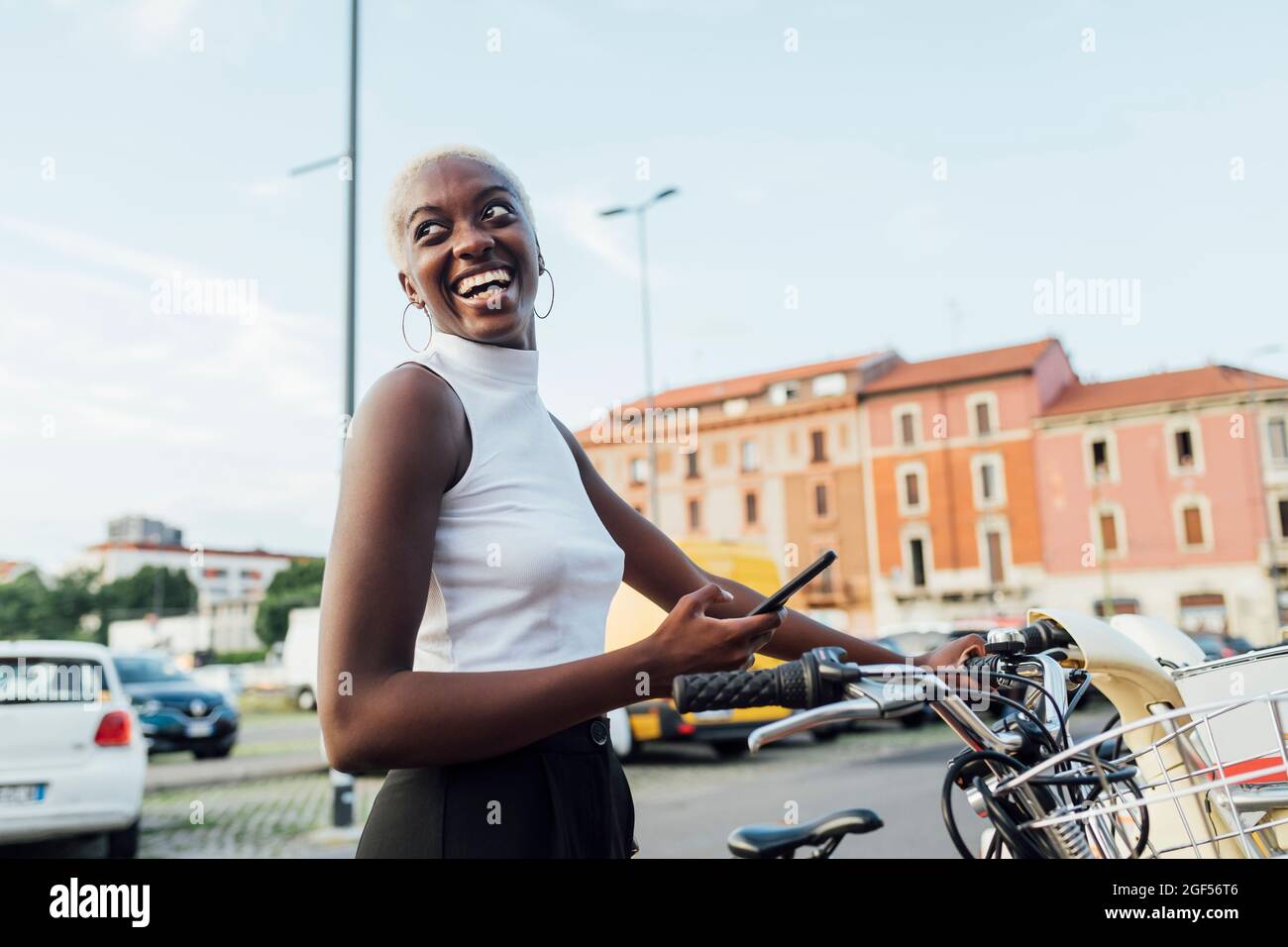 Glückliche Frau, die das Fahrrad über das Smartphone in der Stadt entriegelt Stockfoto