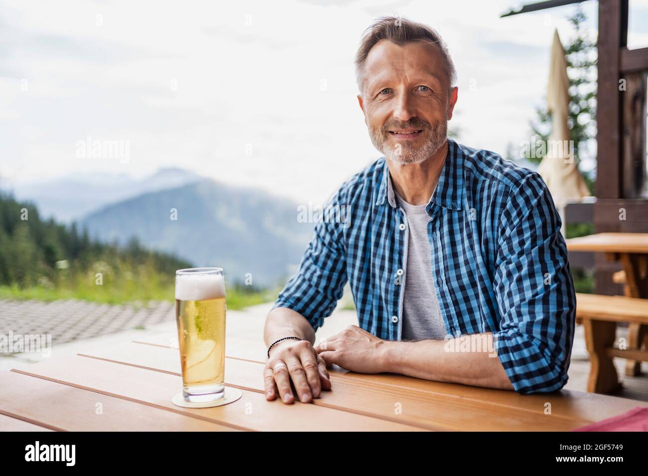 Lächelnder Mann, der mit einem Bierglas am Bartisch sitzt Stockfoto