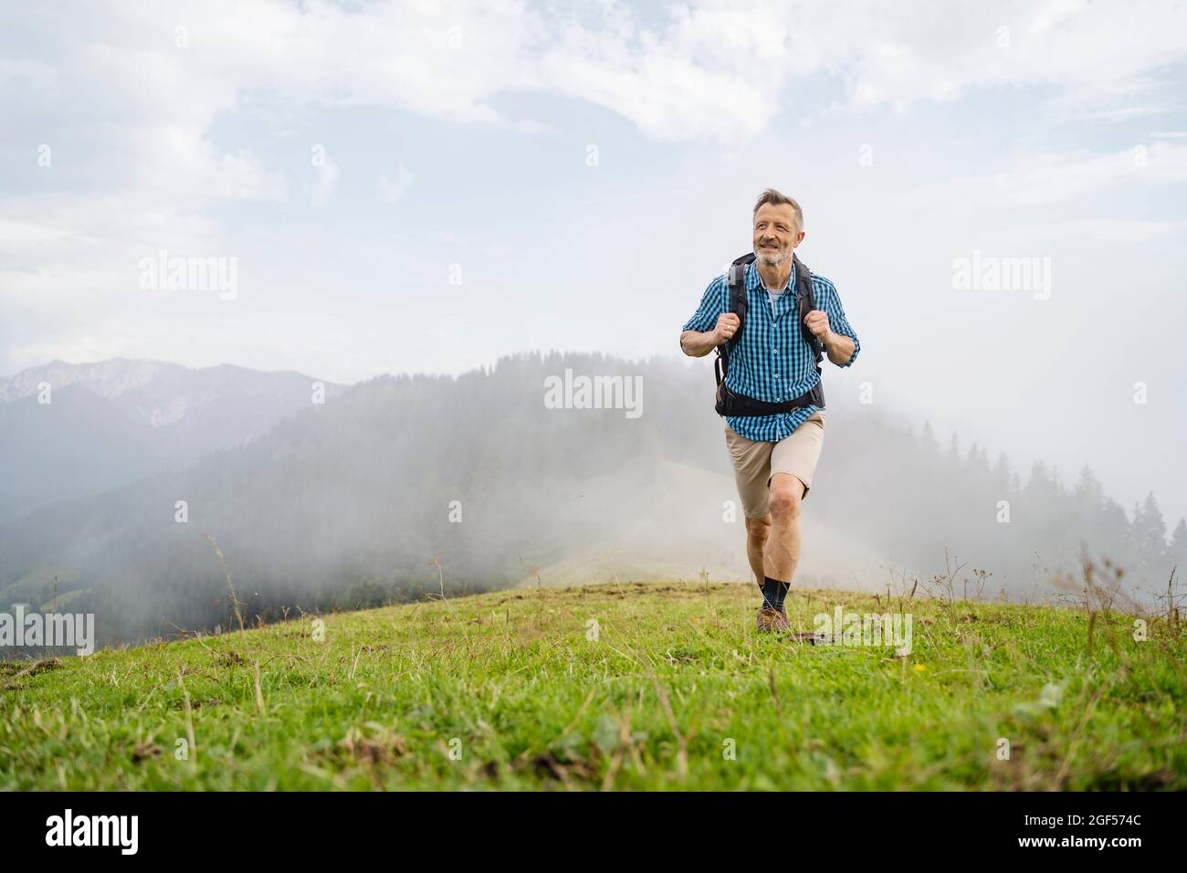 Reifer männlicher Wanderer, der auf dem Berg läuft Stockfoto