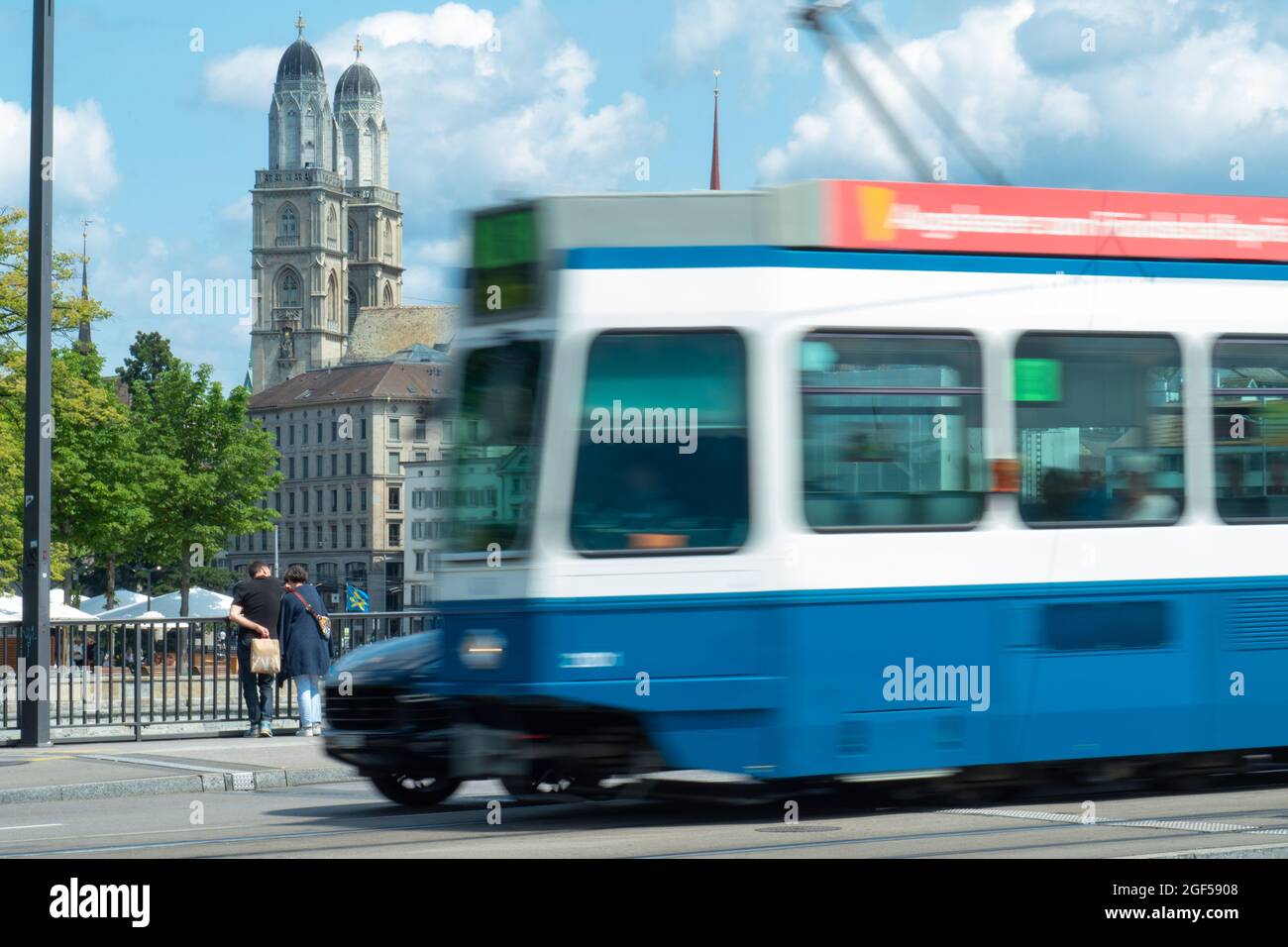 Zürich, Schweiz - 13. Juli 2019: Eine Straßenbahn überholen ein wartender Wagen vor der Grossmünster-Kirche Stockfoto