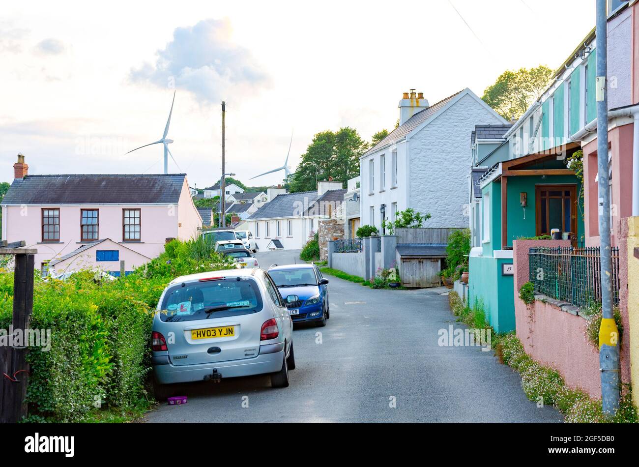 Blick auf die Church Road in Hazelstrand, Milford Haven mit großen Windmühlen in der Ferne, die sauberen Strom erzeugen. Stockfoto