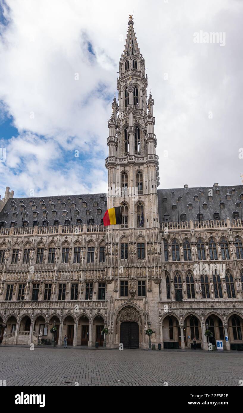 Brüssel, Belgien - 31. Juli 2021: Porträt des historischen Rathauses aus beigefarbenem Stein mit Turm und Turm in der Mitte unter blauer Wolkenlandschaft. Dunkles Dach und gepflegt Stockfoto