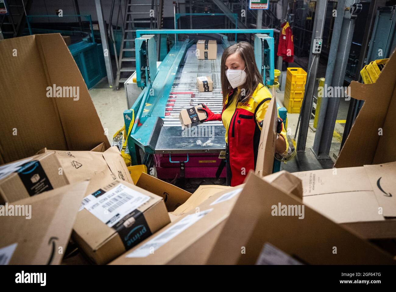 19. August 2021, Baden-Württemberg, Köngen: Adriana Tec, Dispatcher im DHL Paketzentrum in Köngen, platziert Pakete während ihrer Nachtschicht auf einer Montagelinie. (An dpa: 'Hohes Paketvolumen im DHL-Distributionszentrum - Corona oder nicht') Foto: Christoph Schmidt/dpa Stockfoto