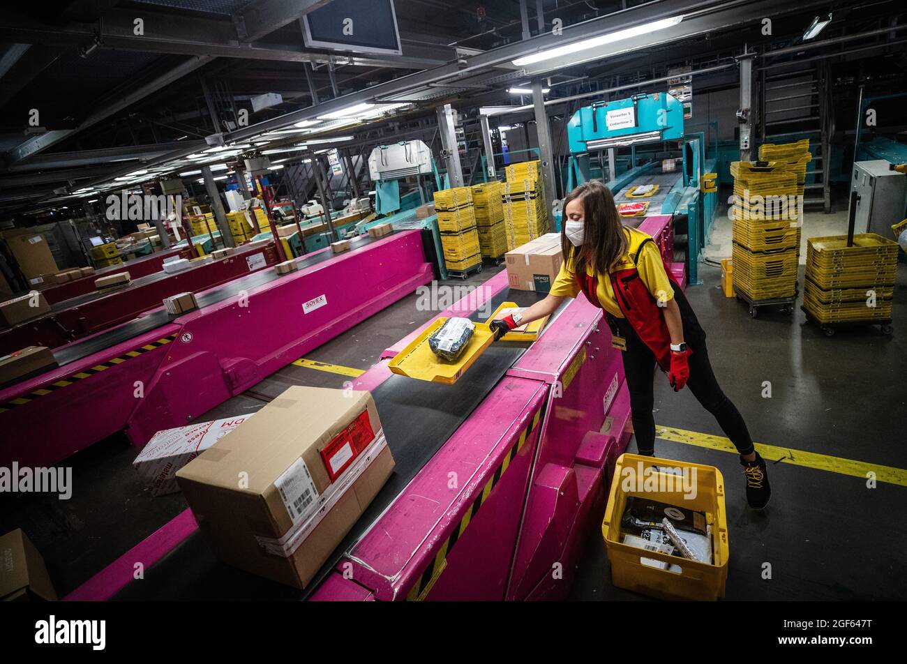 19. August 2021, Baden-Württemberg, Köngen: Adriana Tec, Dispatcher im DHL Paketzentrum in Köngen, platziert Pakete während ihrer Nachtschicht auf einer Montagelinie (an dpa: 'Hohes Paketvolumen im DHL-Versandzentrum - Corona or not') Foto: Christoph Schmidt/dpa Stockfoto