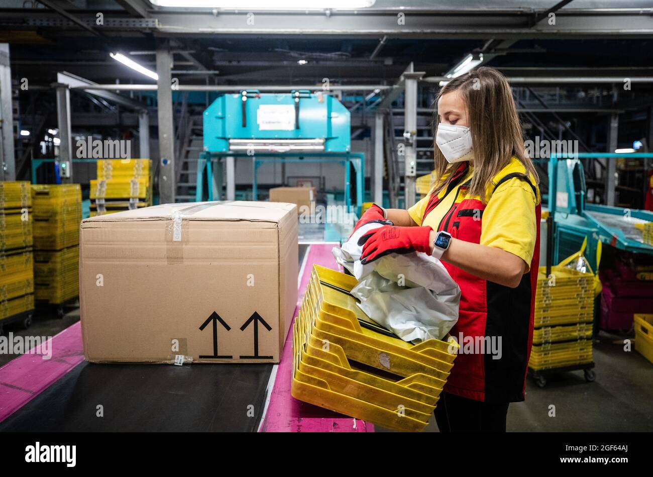 19. August 2021, Baden-Württemberg, Köngen: Adriana Tec, Dispatcher im DHL Paketzentrum in Köngen, platziert Pakete während ihrer Nachtschicht auf einer Montagelinie (an dpa: 'Hohes Paketvolumen im DHL-Versandzentrum - Corona or not') Foto: Christoph Schmidt/dpa Stockfoto