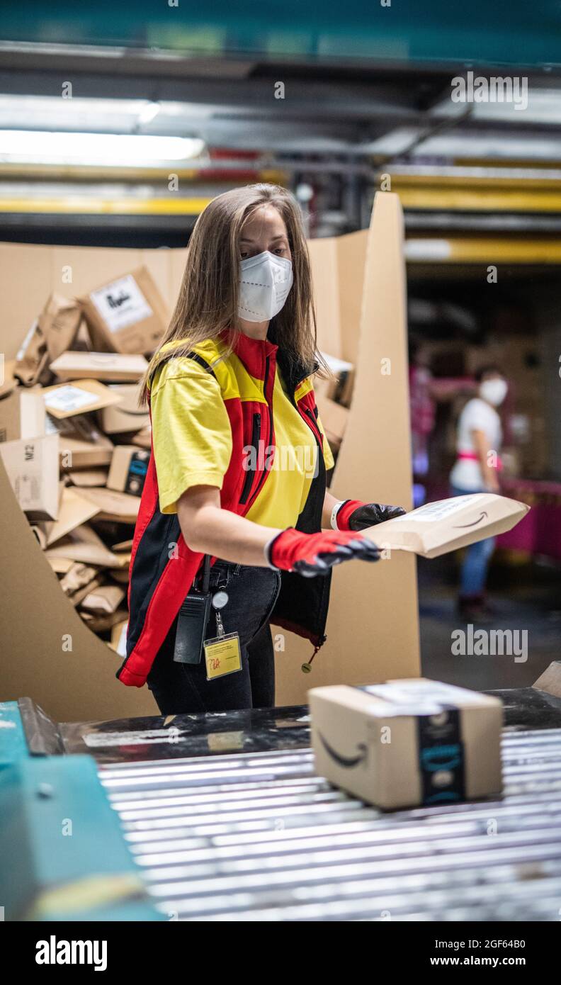 19. August 2021, Baden-Württemberg, Köngen: Adriana Tec, Dispatcher im DHL Paketzentrum in Köngen, platziert Pakete während ihrer Nachtschicht auf einer Montagelinie (an dpa: 'Hohes Paketvolumen im DHL-Versandzentrum - Corona or not') Foto: Christoph Schmidt/dpa Stockfoto