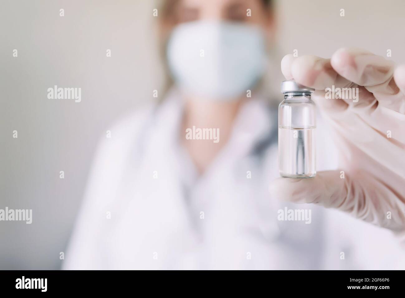 Ärztin oder Krankenschwester in Uniform, Handschuhe, Gesichtsmaske mit Impfstoffflasche Stockfoto