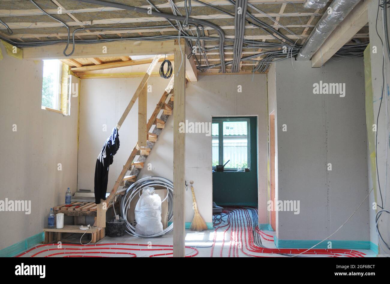 Ein Blick vom Inneren des Hauses im Bau mit Fiberglas isolierte Decke, Innen-elektrische Verkabelung in Metallrohr, Trockenbau, warmes Wasser unter Stockfoto