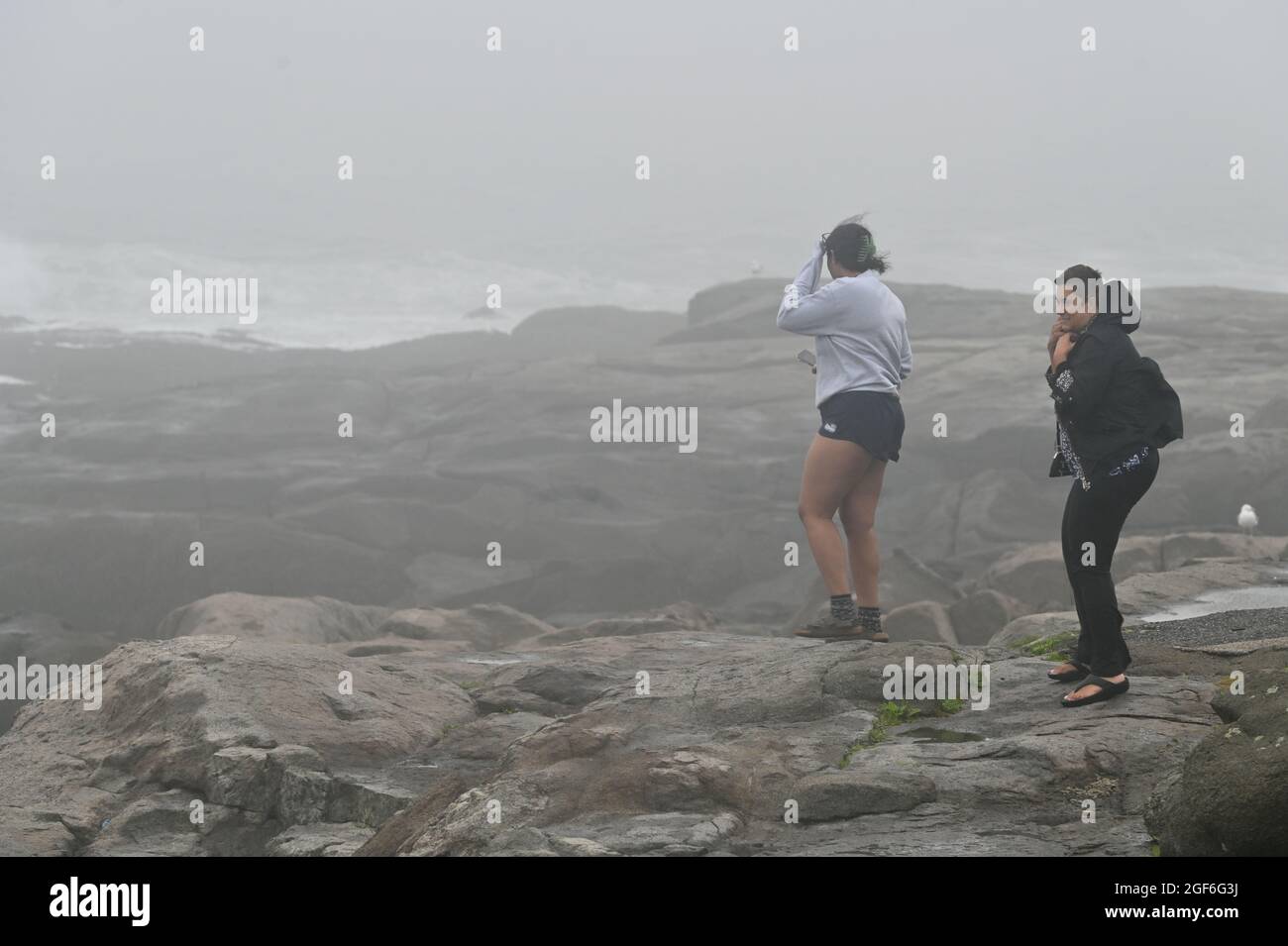 Maine, Usa. August 2021. Frauen beobachten, wie der Wind aufbläst und die Wellen am York Beach gegen die Felsen krachen. Kredit: SOPA Images Limited/Alamy Live Nachrichten Stockfoto