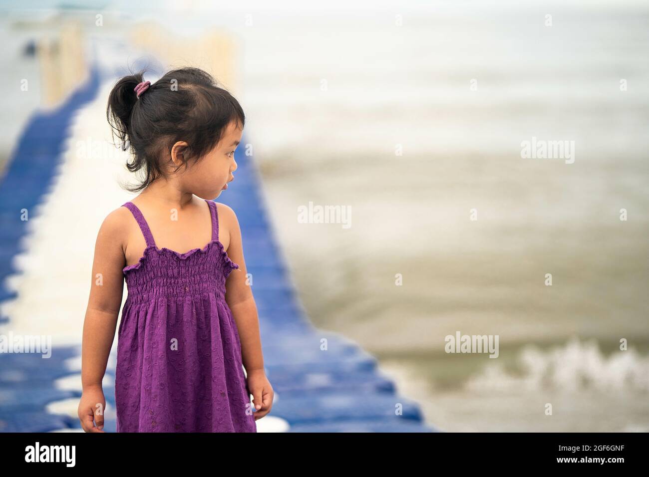 Niedliches kleines Thai-Mädchen, das auf einem modularen schwimmenden Dock aus Kunststoff läuft Stockfoto