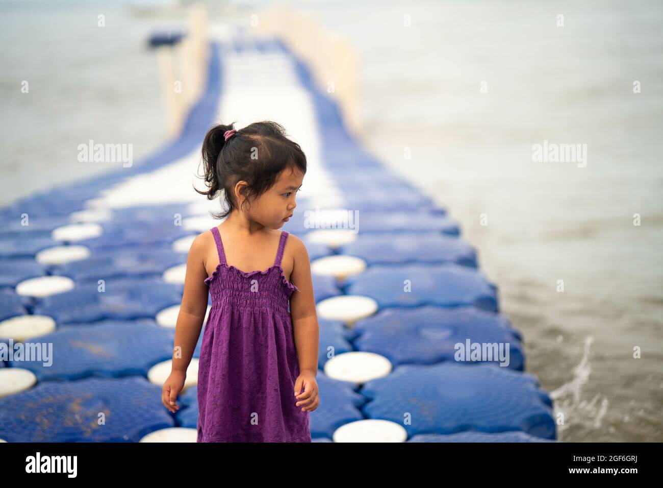 Niedliches kleines Thai-Mädchen, das auf einem modularen schwimmenden Dock aus Kunststoff läuft Stockfoto