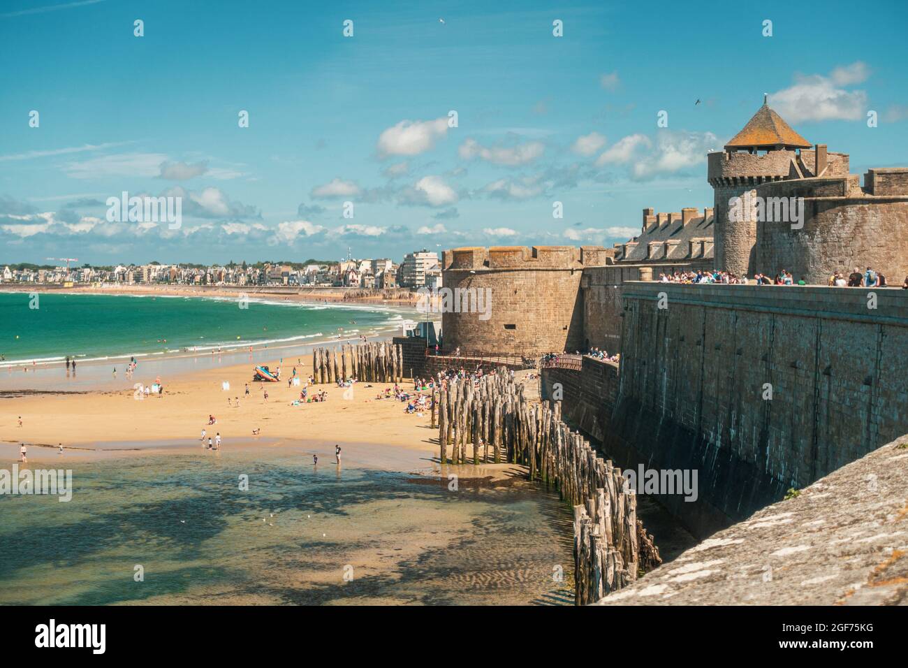 Der Strand und die Menschen unter den Stadtmauern, von der mittelalterlichen Festung unter den Stadtmauern in Saint Malo, Frankreich, Bretagne Stockfoto